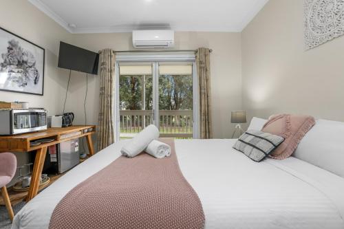 a bedroom with a bed and a desk and a window at Galbraith Beach Studio 1 - steps away from beach in Marengo