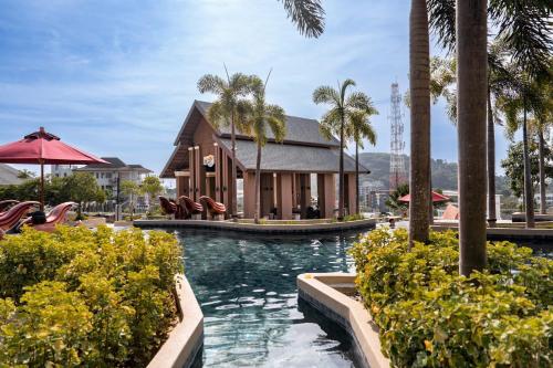 a pool at a resort with a building and palm trees at Surin Beach View Phuket in Ban Lum Fuang