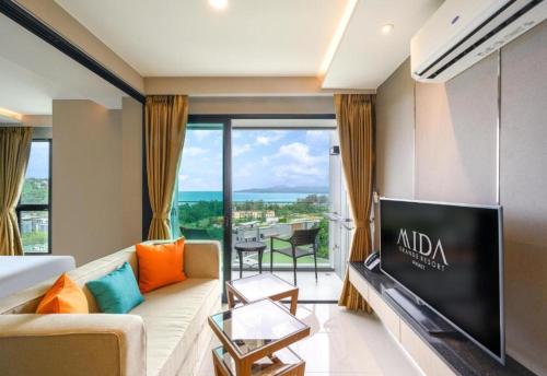 a living room with a couch and a tv at Surin Beach View Phuket in Ban Lum Fuang