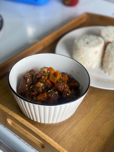 Eine Schüssel Rindfleischeintopf auf einem Tablett mit einem Teller Brot in der Unterkunft Legit Motel in Kampala