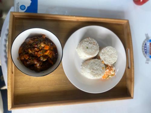 ein Tablett mit zwei Schüsseln mit Essen und Brot in der Unterkunft Legit Motel in Kampala
