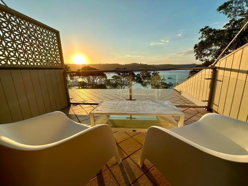a patio with a table and chairs and the sunset at BlueWater Penthouse GuestSuite 3B in Newport