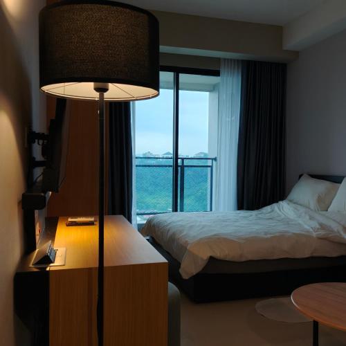 a hotel room with a bed and a lamp and a window at Saffron Noble Apartment in Citaringgul 1