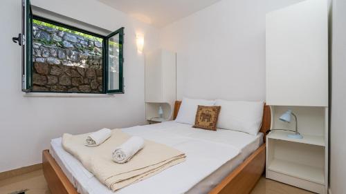 a bedroom with a bed with white sheets and a window at Grand view Orasac by Villas Guide in Dubrovnik