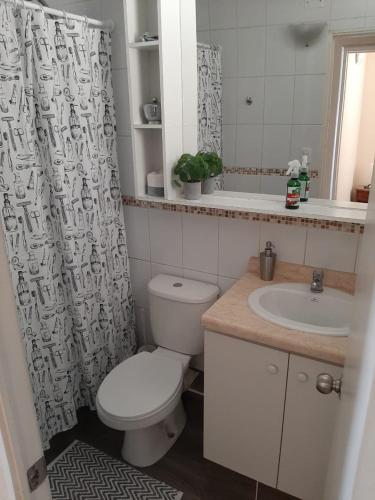 a bathroom with a toilet and a sink and a shower curtain at Galicia in La Serena