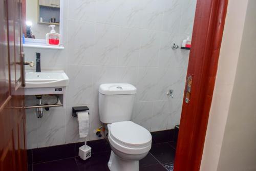 a bathroom with a white toilet and a sink at Stayride Homes in Ruaka