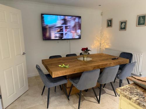 a dining room table with chairs and a television on the wall at Carreg Llwyd in Caerphilly