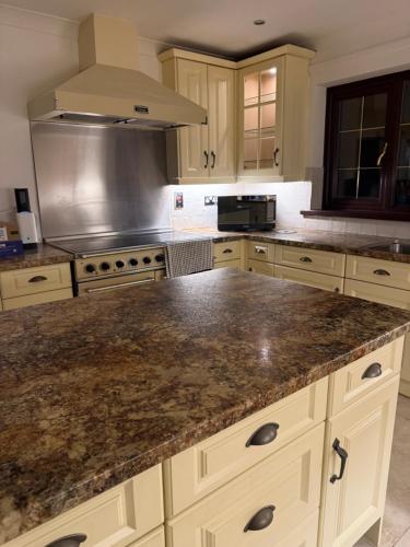 a kitchen with white cabinets and a granite counter top at Carreg Llwyd in Caerphilly