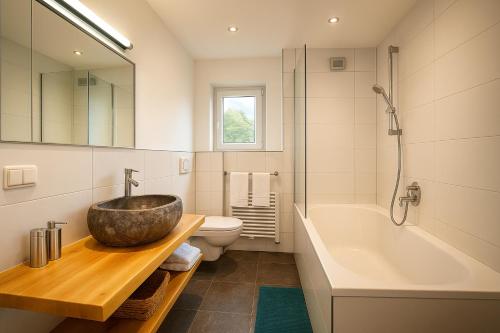 een badkamer met een wastafel, een bad en een toilet bij Haus am Lift in Kleinarl