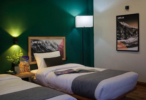 1 Schlafzimmer mit 2 Betten und einer grünen Wand in der Unterkunft Hotel Demanchi By The Leaf in Kārandūkai