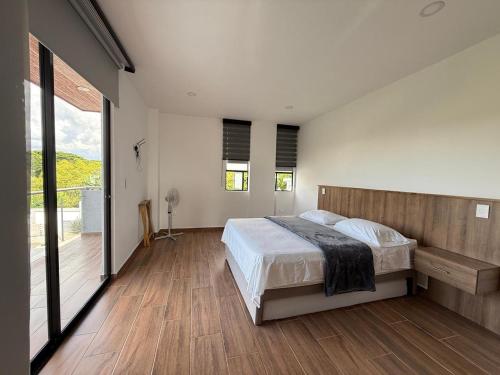 een slaapkamer met een bed en een houten vloer bij Casa boreales in Quimbaya