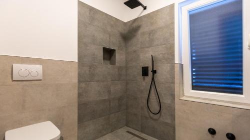 un bagno con doccia, WC e finestra di Villa Dolina Opuzen by Villas Guide a Podgradina