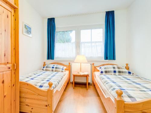 オストゼーバート・ゼリンにあるFerienwohnungen in Sellin D 091.020-25の青いカーテン付きのベッドルームのベッド2台