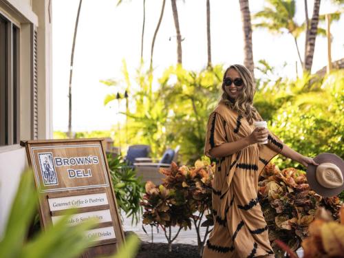 une femme en robe tenant un téléphone portable dans l'établissement Fairmont Orchid, à Waikoloa