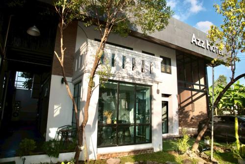 a white building with a tree in front of it at Azz Hotel in Chiang Mai