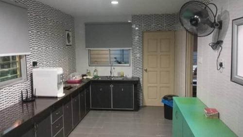 een keuken met zwarte kasten en een gele deur bij mulia homestay in Teluk Intan