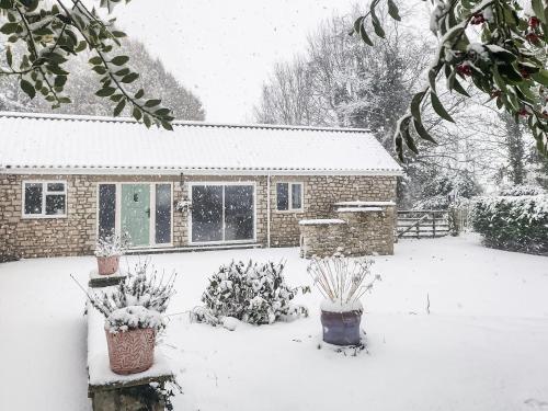 ein schneebedecktes Haus mit Pflanzen im Hof in der Unterkunft Silent Springs in Nawton