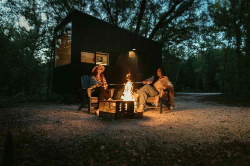 高泉Postcard Cabins Gilchrist Springs, Outdoor Collection by Marriott Bonvoy的三人坐在小屋前的火炉旁