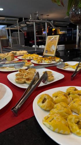 un tavolo rosso sormontato da piatti di pasticcini e torte di Hotel Áster ad Alagoinhas