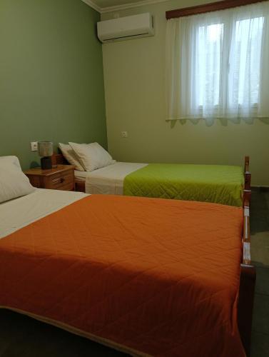 a bedroom with two beds with green sheets and a window at ainos cottage in Kambitsáta