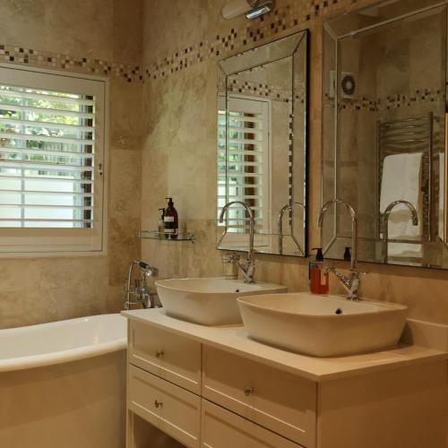 a bathroom with two sinks and a tub and a mirror at Kleinhof in Franschhoek