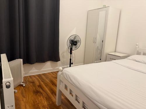 een slaapkamer met een wit bed en een ventilator bij Rayan's Lodge Stratford London by OYO in Londen
