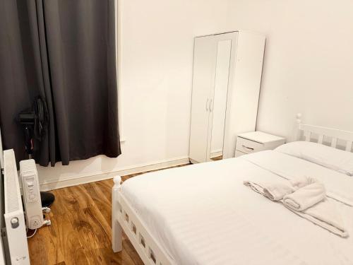 een slaapkamer met 2 witte bedden en een spiegel bij Rayan's Lodge Stratford London by OYO in Londen