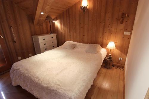 ヴァル・トランスにあるPeclet Appartements VTIの白いベッドと木製の壁が備わるベッドルーム1室が備わります。