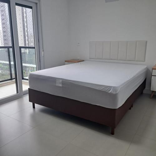 a large bed in a room with a large window at Apto 3 quartos Centro Torres RS in Torres