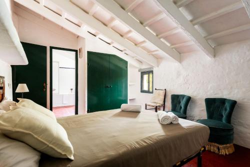 una camera con un grande letto e due sedie verdi di Finca Biniparrell Vell a Sant Lluís