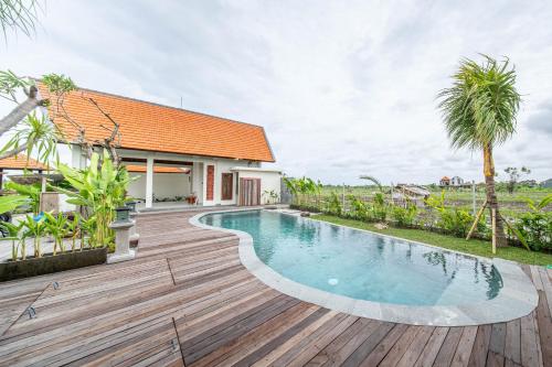 a wooden deck with a swimming pool and a house at Svadarma Bali Villa in Darmasaba