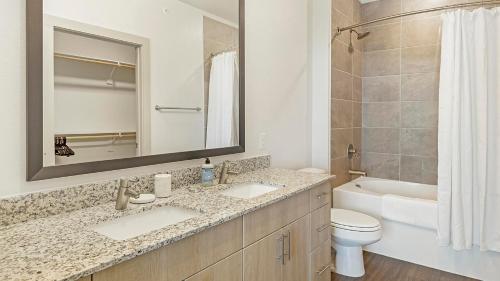 a bathroom with a sink and a toilet and a mirror at Landing Apartments - The Quinn in Anna