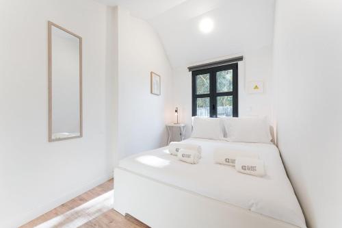 a white bedroom with a white bed and a window at GuestReady - charming retreat in Porto in Porto