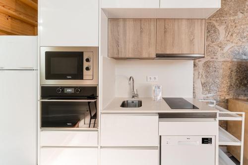 a white kitchen with a sink and a microwave at GuestReady - charming retreat in Porto in Porto