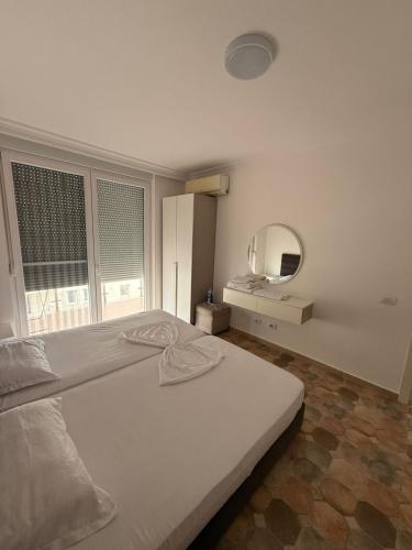a white bedroom with a bed and a mirror at Holiday home Shengjin k in Shëngjin