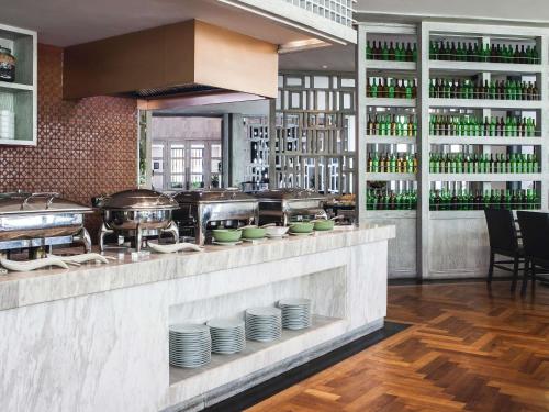 a restaurant with a counter with plates and drinks at Mövenpick Hotel Sukhumvit 15 Bangkok in Bangkok