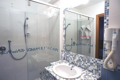 a bathroom with a sink and a glass shower at Hotel Sirio in Lido di Camaiore