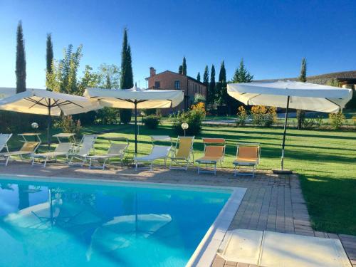 uma piscina com cadeiras e guarda-sóis ao lado em Agriturismo Marinello em Pienza