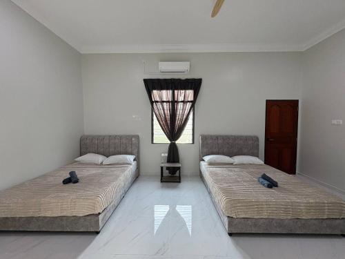 two beds in a white room with a window at Sasuka Inn Rusila in Marang