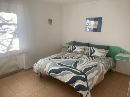Schlafzimmer mit einem Bett mit einer grünen und weißen Bettdecke in der Unterkunft Appartamento Ape Verde in Piano dʼArta