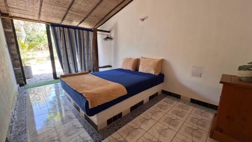 een slaapkamer met een bed met blauwe lakens en een raam bij Footsteps Eco-Lodge in Gunjur