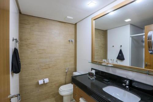 a bathroom with a sink and a toilet and a mirror at Flat Radisson Hotel Belem in Belém