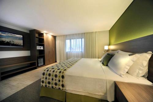 a hotel room with a large bed and a television at Flat Radisson Hotel Belem in Belém