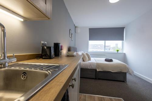 a kitchen with a sink and a bed in a room at Derwent Court Aparthotel in Derby