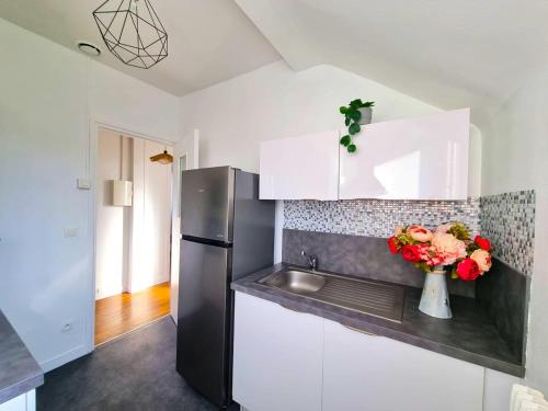 eine Küche mit Kühlschrank und einer Blumenvase in der Unterkunft Emeraude du centre Elbeuf Confort et Elegance in Elbeuf