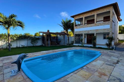 a dolphin swimming in a pool in front of a house at Maré · Casa Maré in Aracati