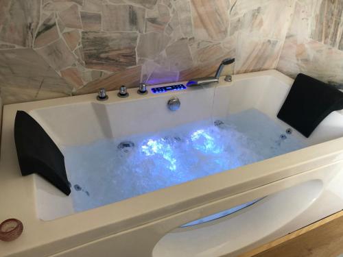 La salle de bains est pourvue d'une baignoire avec de l'eau bleue. dans l'établissement Mauthnerhube Ferienwohnung mit Sauna, Whirlpool, Hüttenfeeling, à Sankt Oswald ob Eibiswald