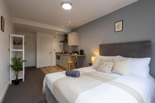 a bedroom with a large white bed and a kitchen at Derwent Court Aparthotel in Derby