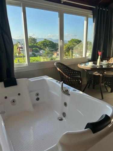 a white bath tub in a room with a window at Pousada Vielas do Rosa - centrinho da praia do rosa in Praia do Rosa