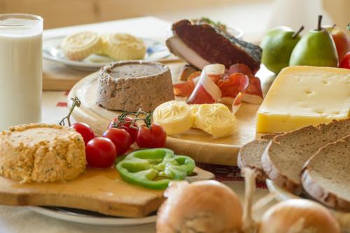 a table topped with bread and vegetables and cheese at Ferienhof Neusacher Moser in Weissensee